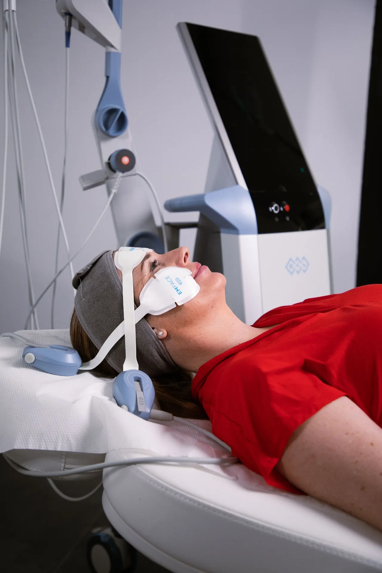 A patient wearing facial applicators during a muscle-stimulation treatment at 23MD