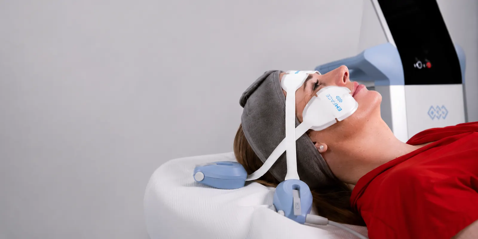 A patient wearing facial applicators during a muscle-stimulation treatment at 23MD