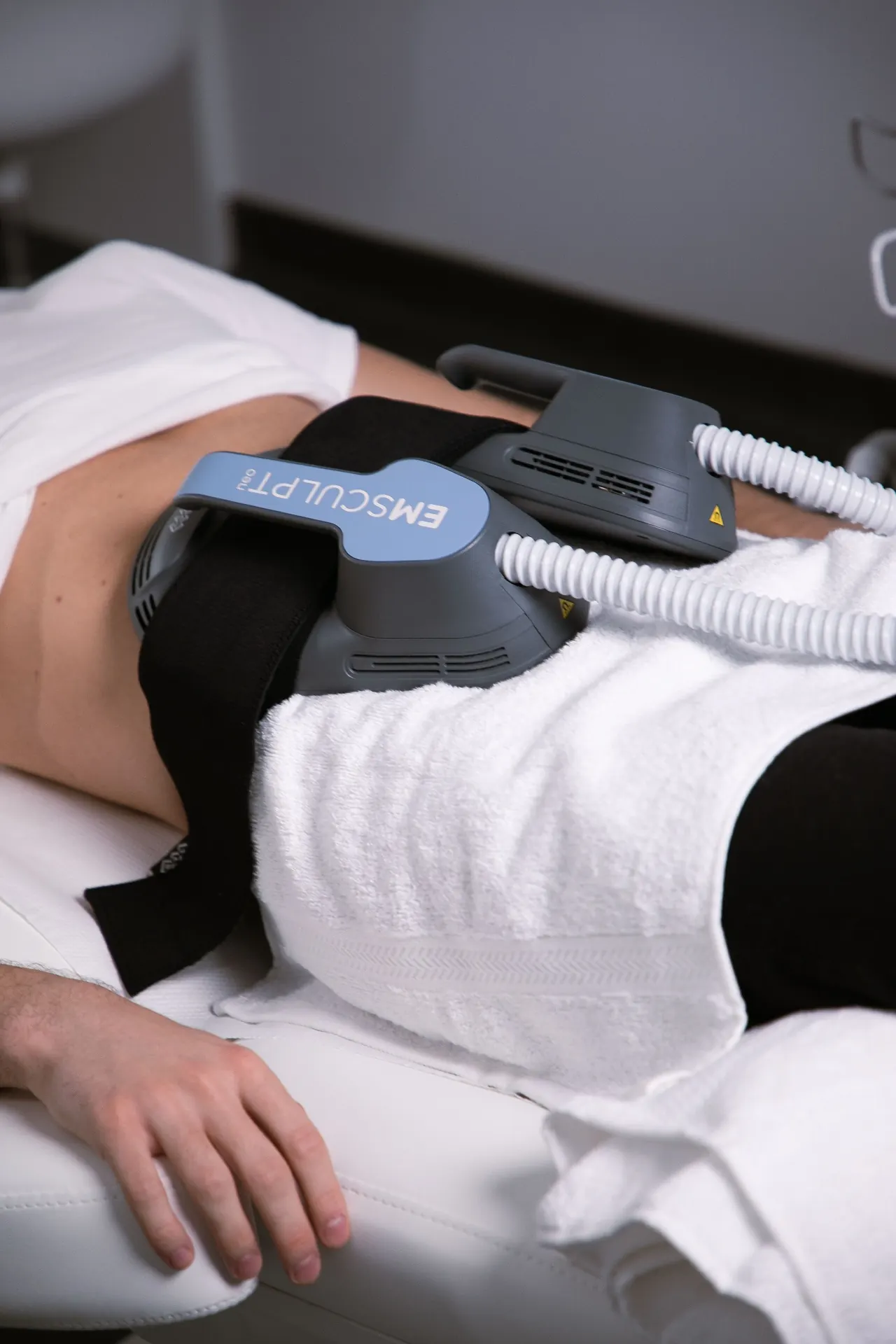 A patient lying on a treatment bed with a body muscle-stimulation applicator at 23MD