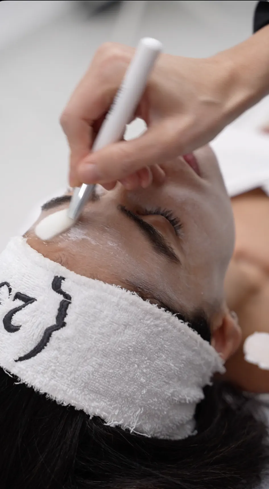 A clinician applying treatment to a patient's forehead during a facial at 23MD