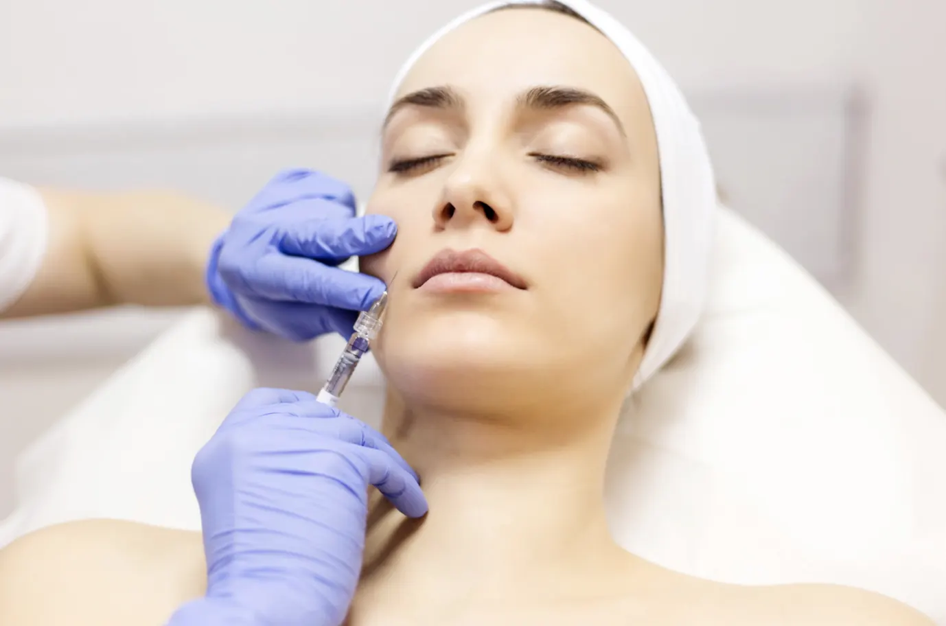 Gloved hands treating a reclining patient's face illustrating an archived health article at 23MD