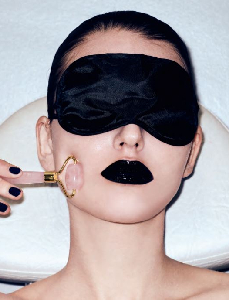 A woman wearing a black eye mask with a brush near her cheek illustrating aesthetic skin care at 23MD