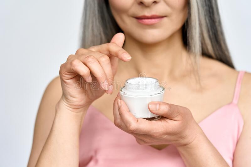 A woman holding a face cream jar illustrating skin care and hormonal health discussion at 23MD