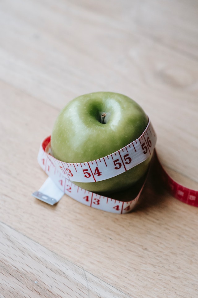 A green apple beside a measuring tape illustrating the subject of metabolic health care at 23MD